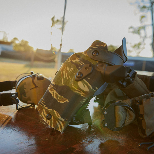 Camouflage holster and ear protection with a blurred outdoor background