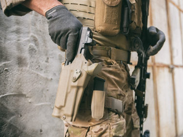 Person in tactical gear drawing a handgun against a blurred background