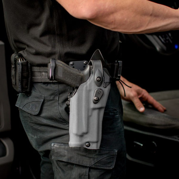 Person wearing a gray gun holster inside a vehicle