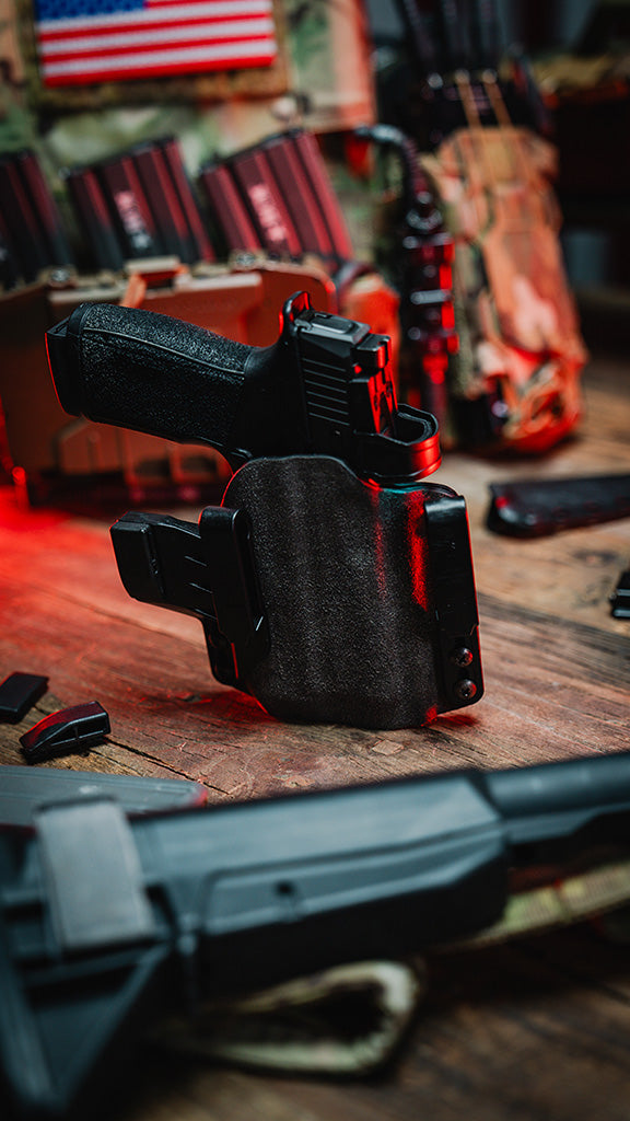 Black gun holster on a wooden surface with American flag in the background