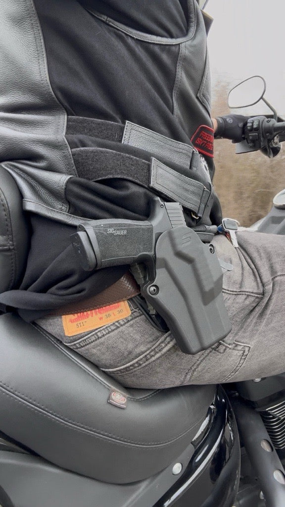 Person sitting on a motorcycle with a gun holster on their leg