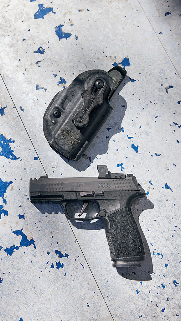 Black handgun and holster on a gray surface with blue speckles
