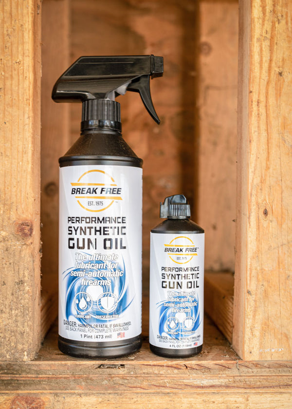 Two bottles of Break Free Performance Synthetic Gun Oil on a wooden surface